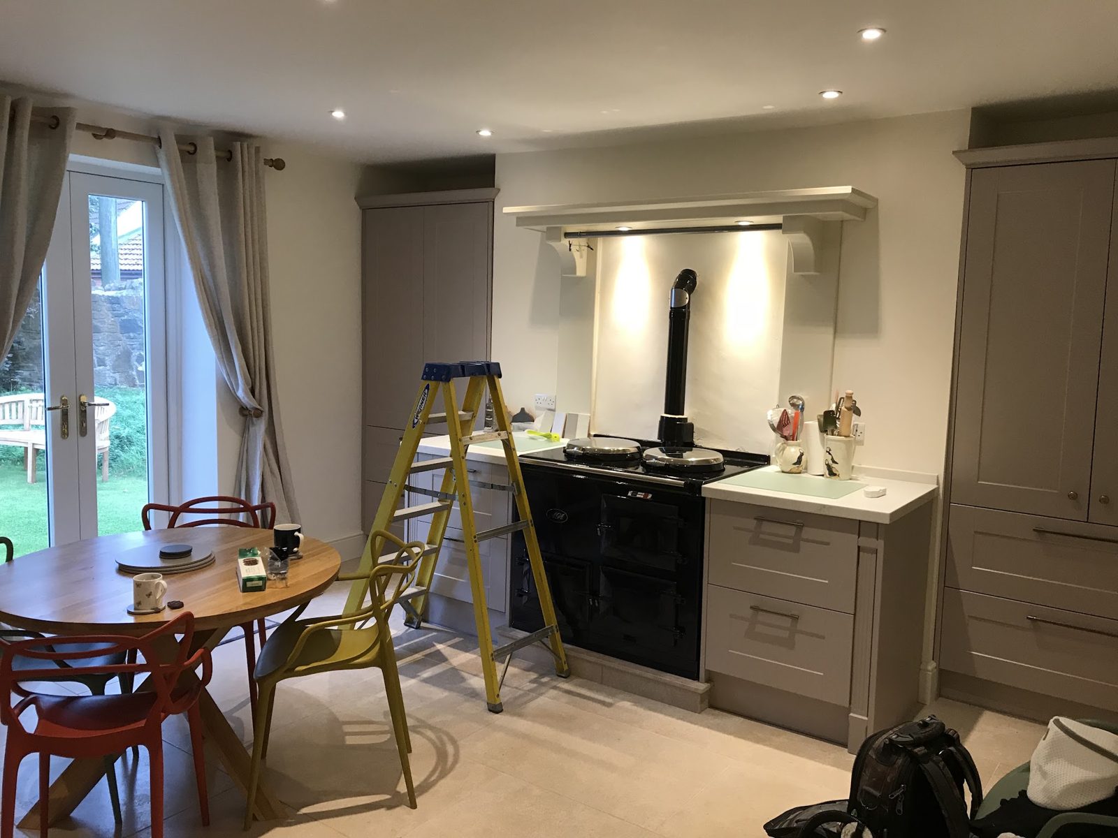 A kitchen with an AGA range lit by two warm downlights under the mantel shelf